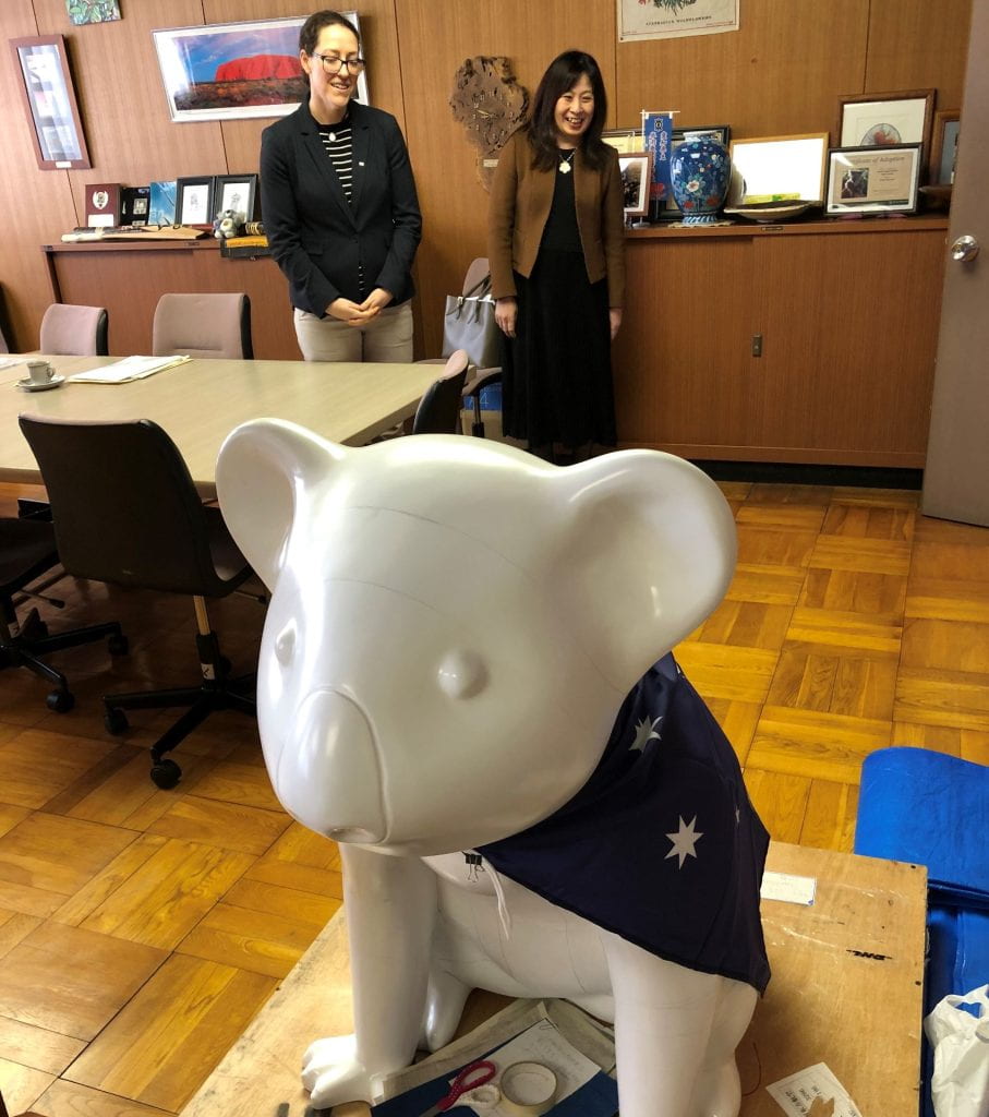 Photo shows a large toy koala and two women smiling in the background.