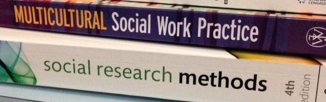 Photos shows three social work textbooks on a shelf.